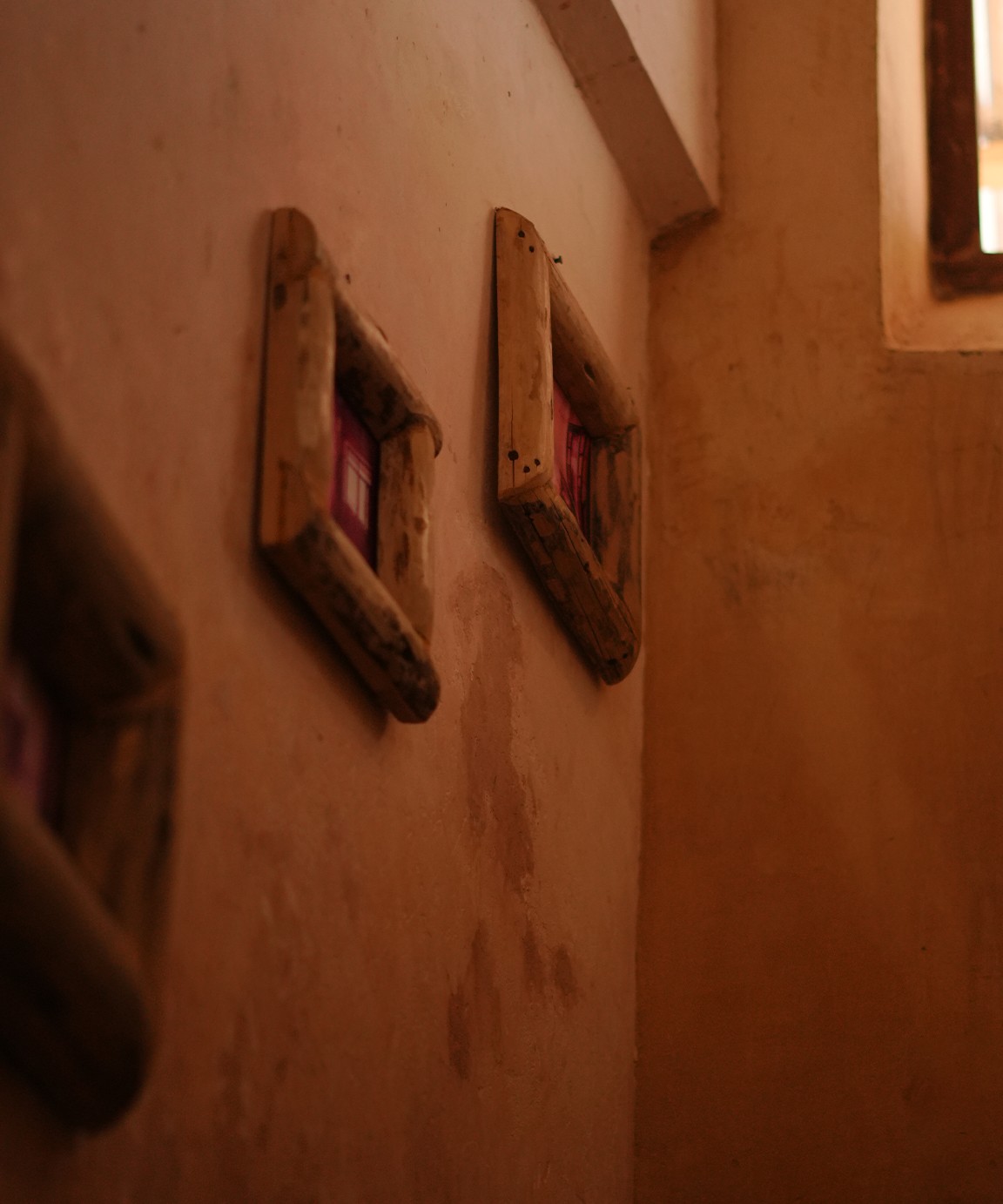 Two driftwood picture frames on a plastered wall