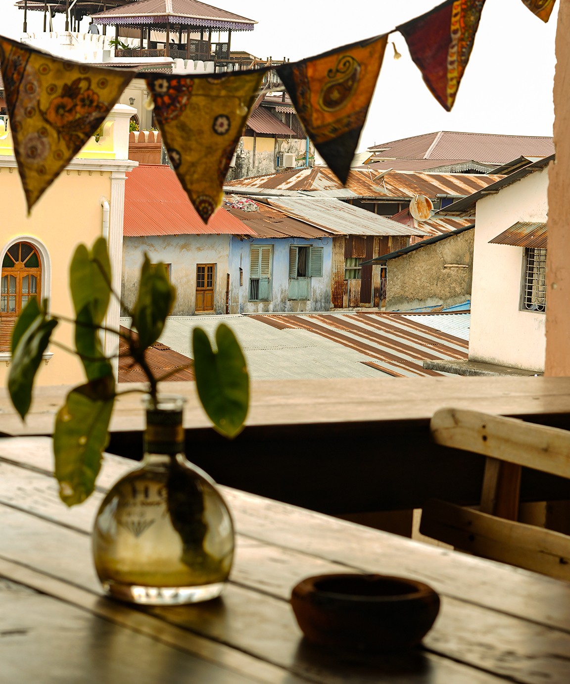 Rooftop table under patterned bunting, looking across Stone Town's tin and tile roofs