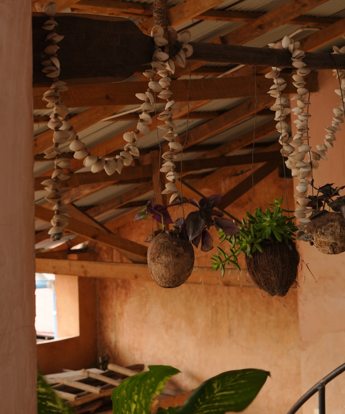 Shell garlands and coconut-husk planters hanging from the roof beams