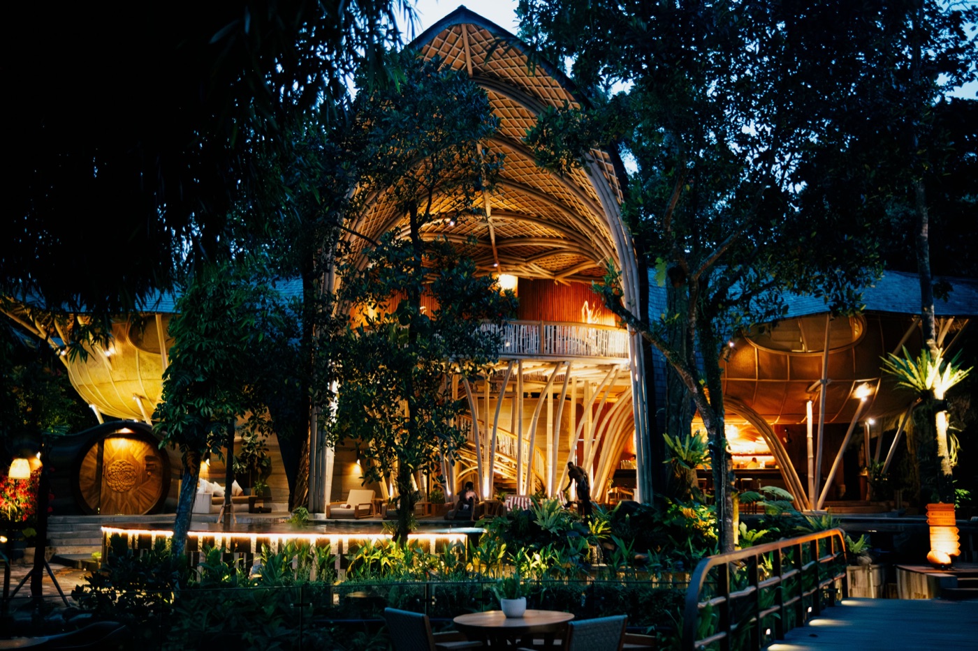 The bamboo lodge at Ulaman lit from within after dark, above the water garden